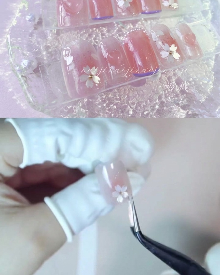 光沢のある爪の上に白い桜の花びらのパーツを慎重に配置しているピンセットのペア。
