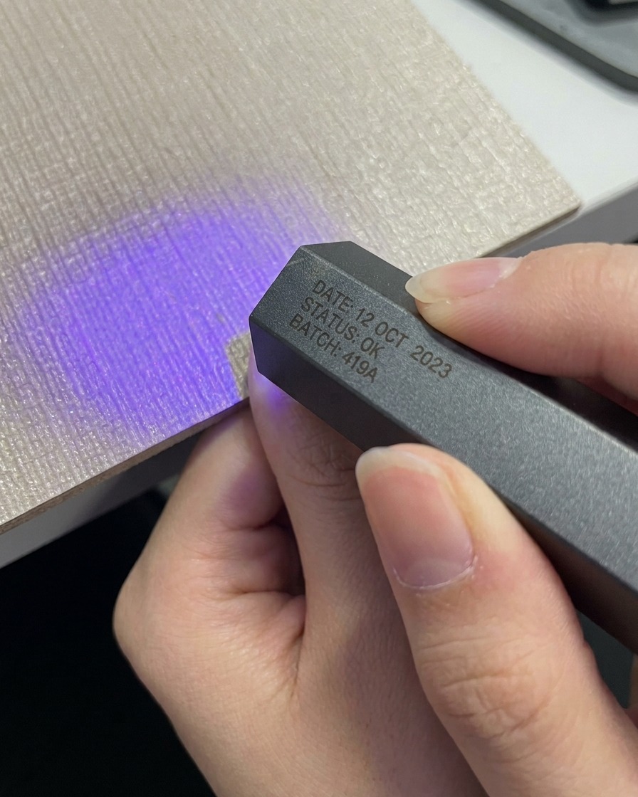 コンパクトなグレーのポータブルUV LEDランプの下に親指を入れている手。