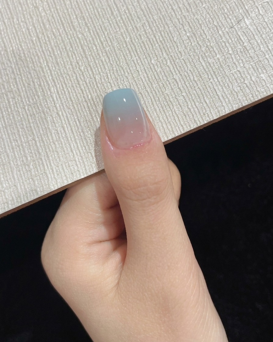 最後のトップコート硬化ステップ中に、ポータブルUV LEDランプの下に配置された親指。