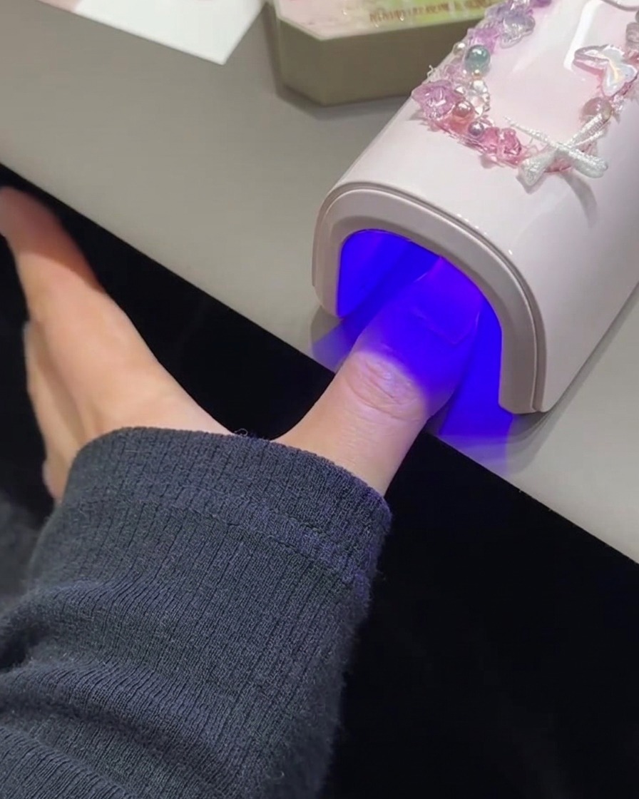 ピンクのUV/LEDランプの下で硬化している爪。