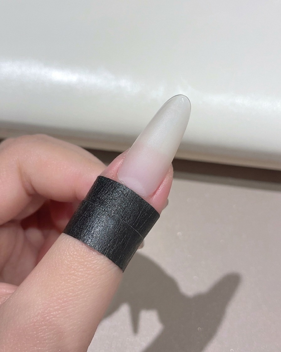 コンパクトなハンディタイプのUV LEDランプの下に置かれた、マニキュアが施された爪。