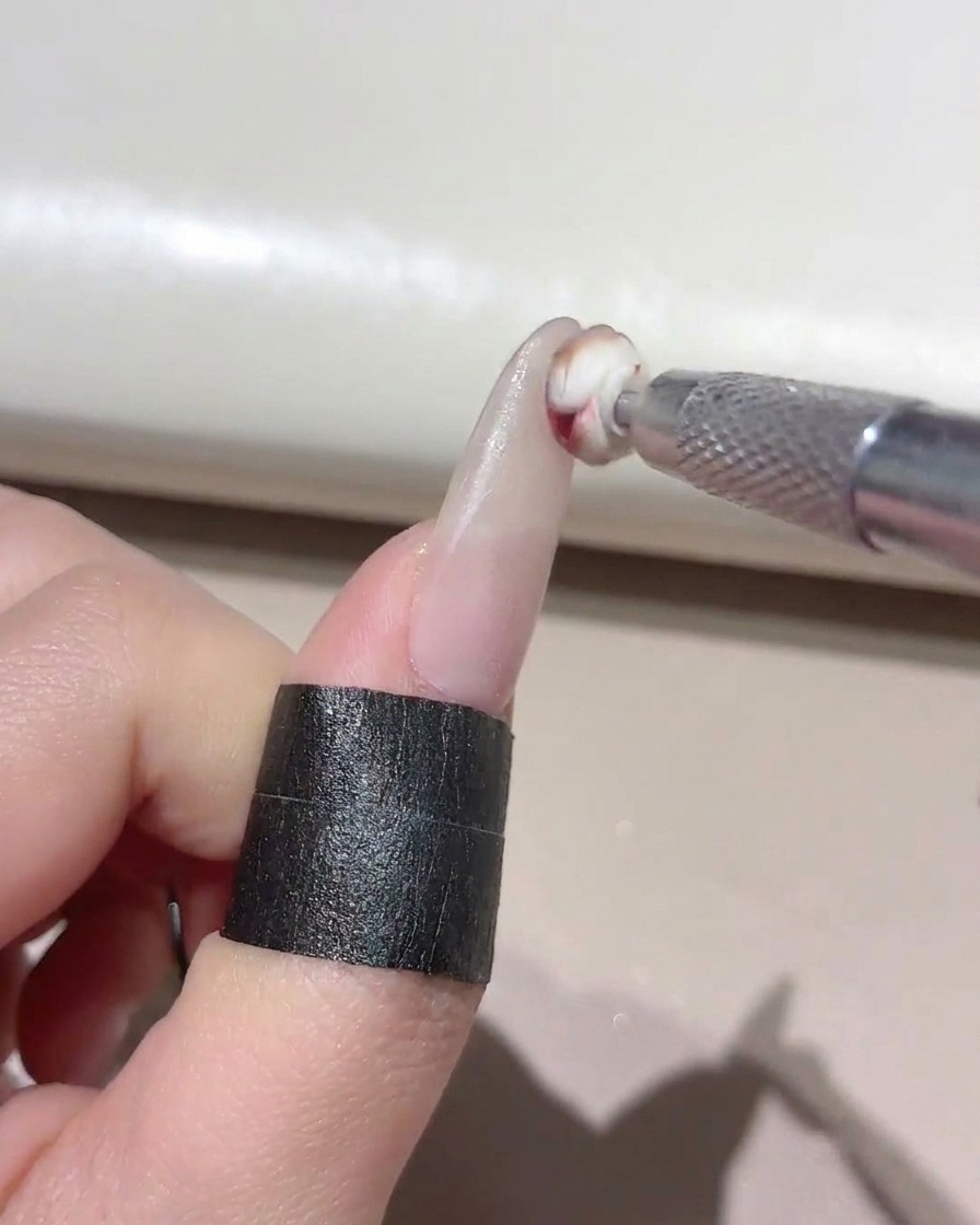 小さなスポンジツールを使い、マニキュアが施された爪の先端に混色したジェルをポンポンと乗せている様子。