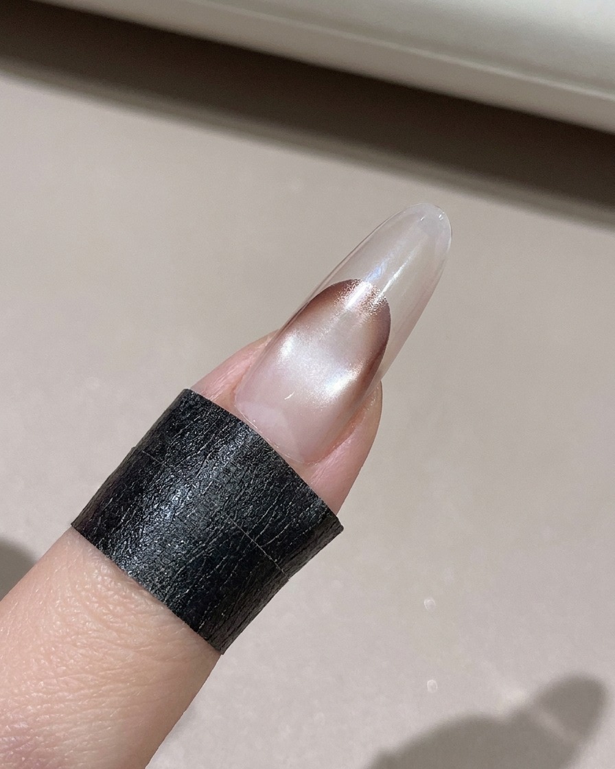 リントフリーのワイプを使って、装飾された爪のエッジからはみ出したジェルをきれいに拭き取っている様子。