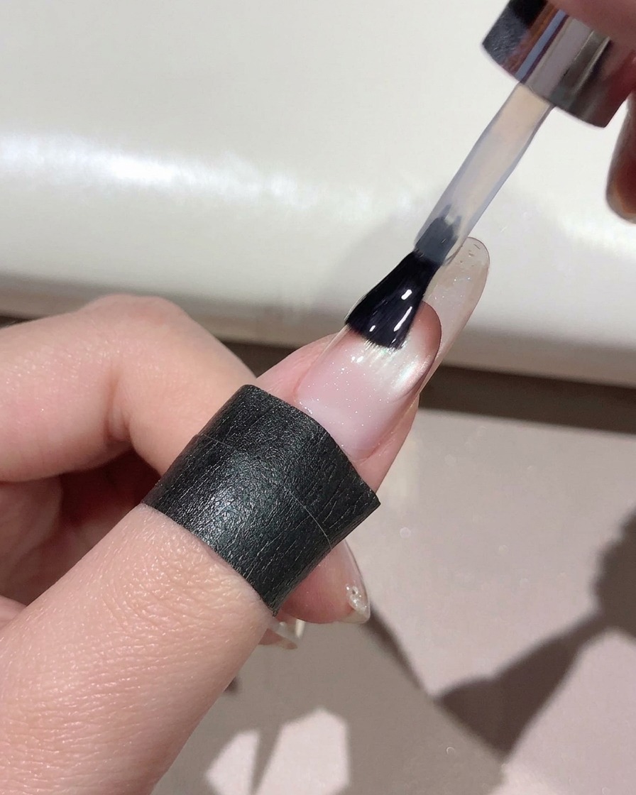 マニキュアが施された爪の表面全体に、ブラシを使ってクリアなトップコートを塗布している様子。
