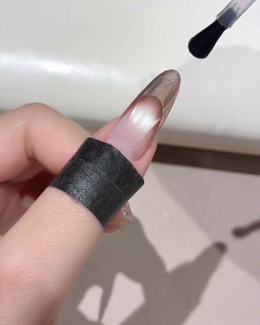 完成したフレンチマニキュアの先端に、ネイルブラシでクリアなトップコートを塗布している様子。