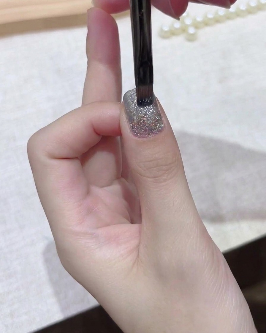 細筆を使用して、ネイルプレート全体にダークジェルの層を均一に滑らかに整えている様子。