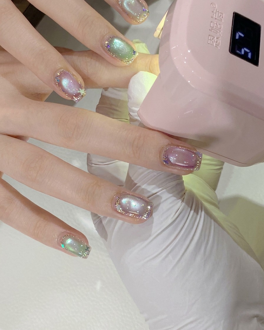 硬化のためにピンクのミニUV/LEDネイルランプの下に配置されたクライアントの手のクローズアップショット。