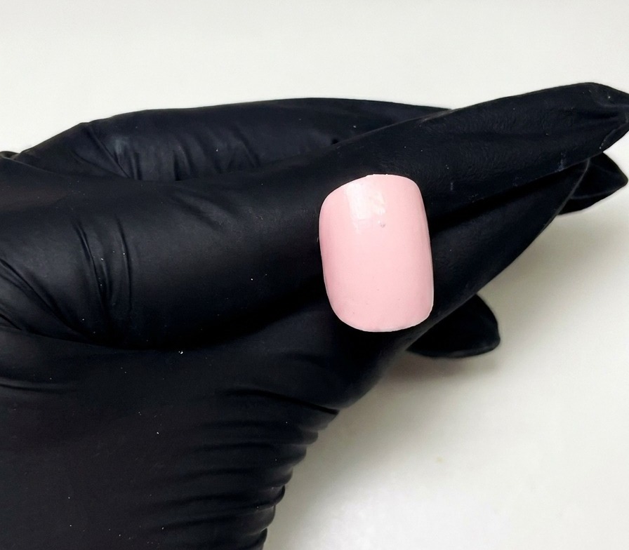 ピンクに塗られた爪の中央上部に、ビルダージェルで小さなドットを置いたアップ画像。