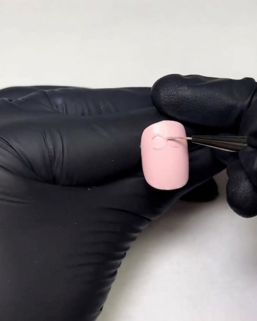 細いライナーブラシを使用して、3Dジェルのリボンのもう片側のループを描いている様子。