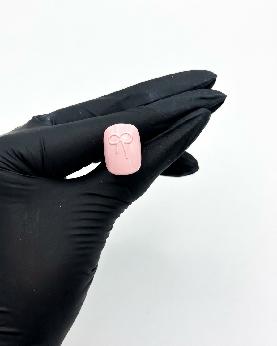 3Dリボンデザインを完成させたピンクのネイルチップを、UV/LEDライトに入れて硬化させている様子。