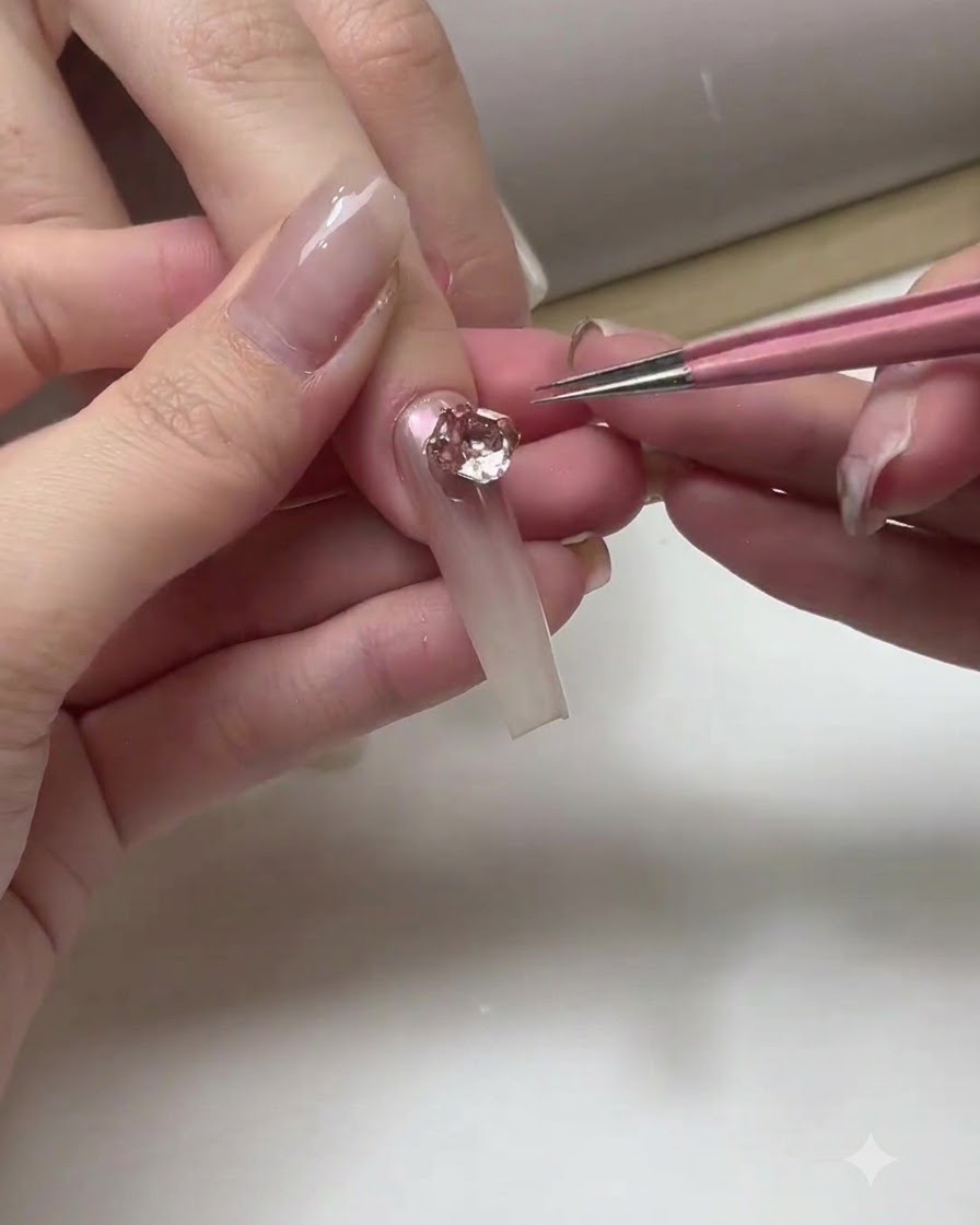ネイリストが完成したオンブレネイルの表面全体にクリアのトップコートを塗布している様子。