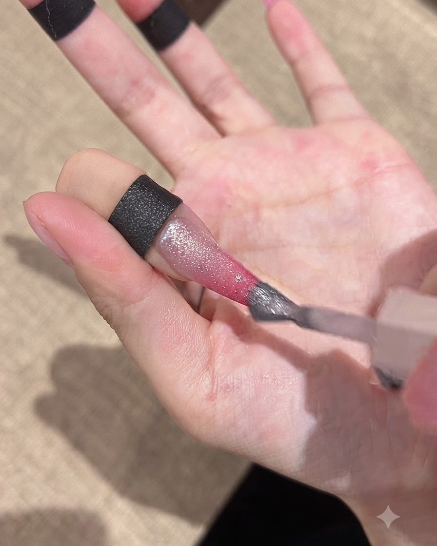 グラデーションネイルの表面に、きらめくキャッツアイジェルをブラシで塗布している様子。