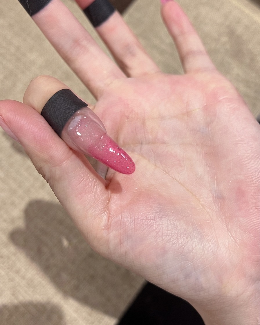 通常の室内照明の下で、微細な反射グリッターの粒子が見えるネイルのクローズアップ。