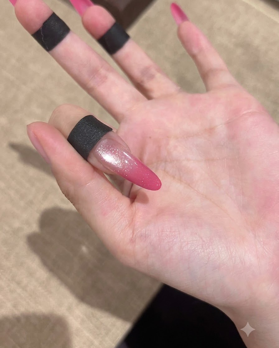 柔らかな背景を背に、ハイグロスな仕上がりを見せる完成したピンクグラデーションのキャッツアイネイル。