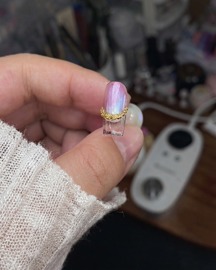 封じられたエッジと完成したデザインの詳細を見せるために持ち上げられた仕上がり済みのネイルパーツ。