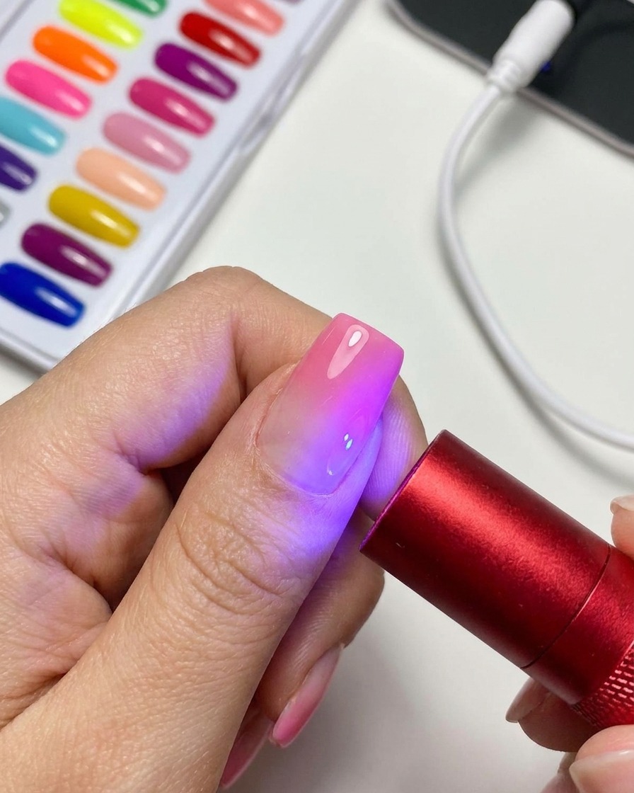 ポータブルな赤いUV/LED硬化ランプが、完成したマグネットジェルネイルを照らしている様子。