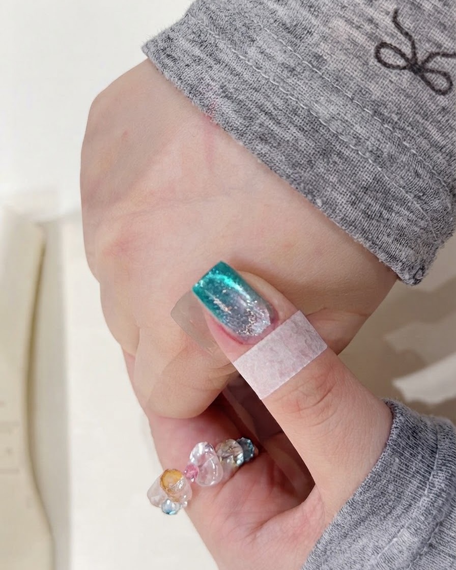 新しく塗布した水彩顔料の層を硬化させるために、UVネイルランプの中に手を置いている様子。