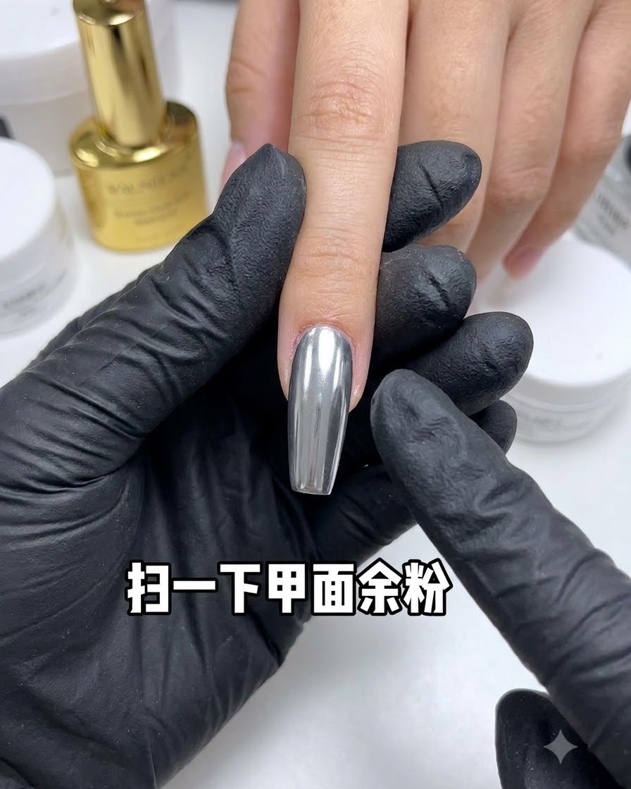 反射するクロムネイルから、ダストブラシで余分なパウダーを払い落としている様子。