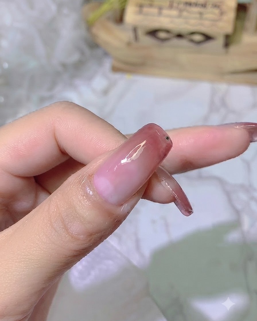 完成したグラデーションネイルの爪先部分に、少量の透明な接着用ジェルを乗せている様子。