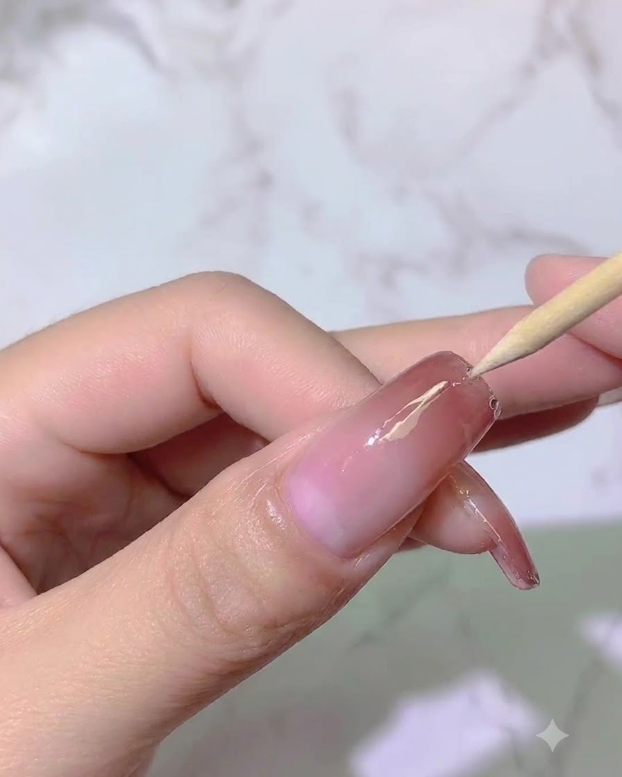 ライトの下で、木製のスティックを使って爪の表面の配置を微調整している様子。