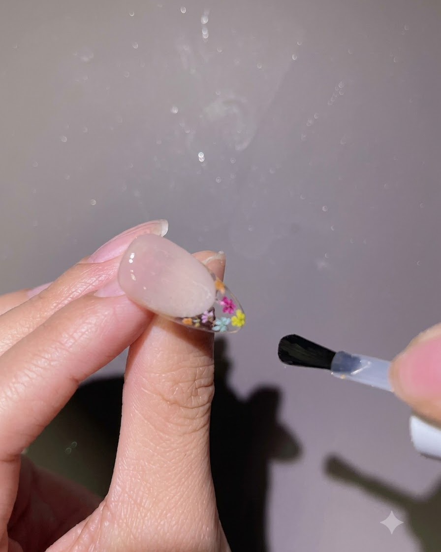 完成したネイルの表面全体に、ブラシで光沢のあるトップコートを塗布している様子。