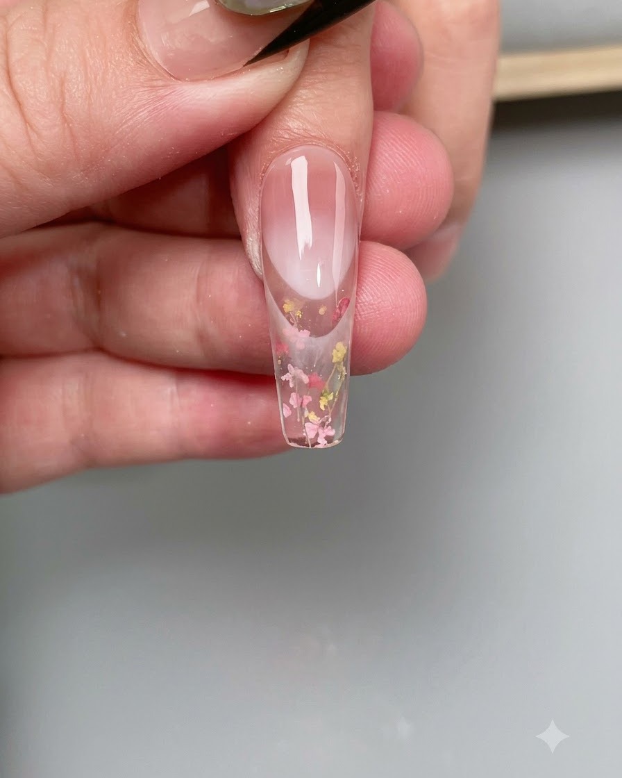 クリアネイルチップの表面に細い筆でベースコートを塗っている様子。