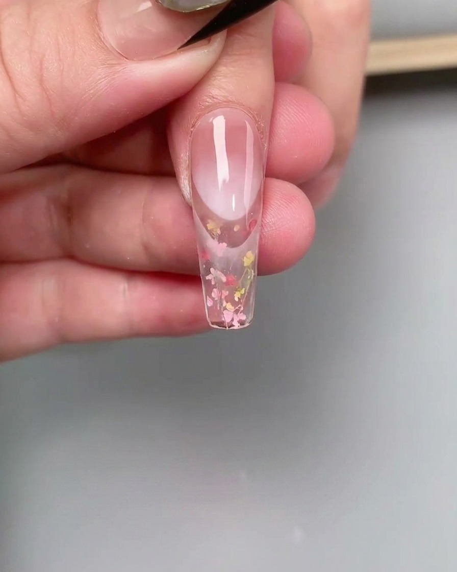 爪の甘皮付近にピンクのカラージェルを塗り、細い筆でグラデーションを作っている様子。