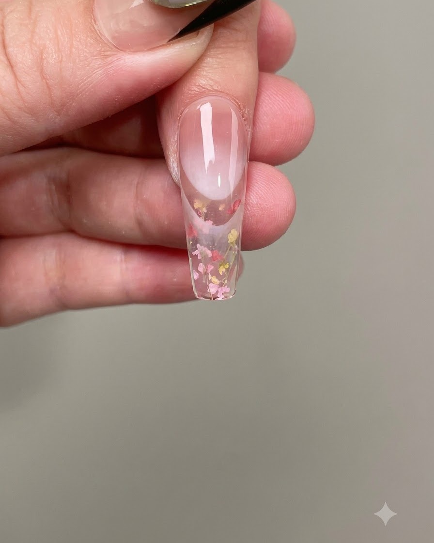 ピンセットを使って、ピンクや黄色の小さな押し花を硬化前のジェルにのせている様子。