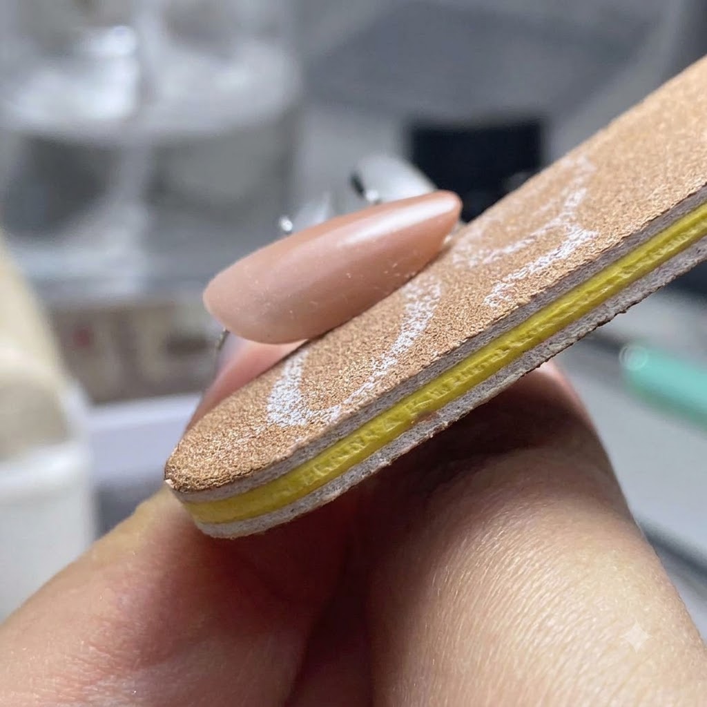 ネイルファイルバッファーを使って、完成したジェルネイルの3つの側面を形を整えながらスムーズにしている様子。