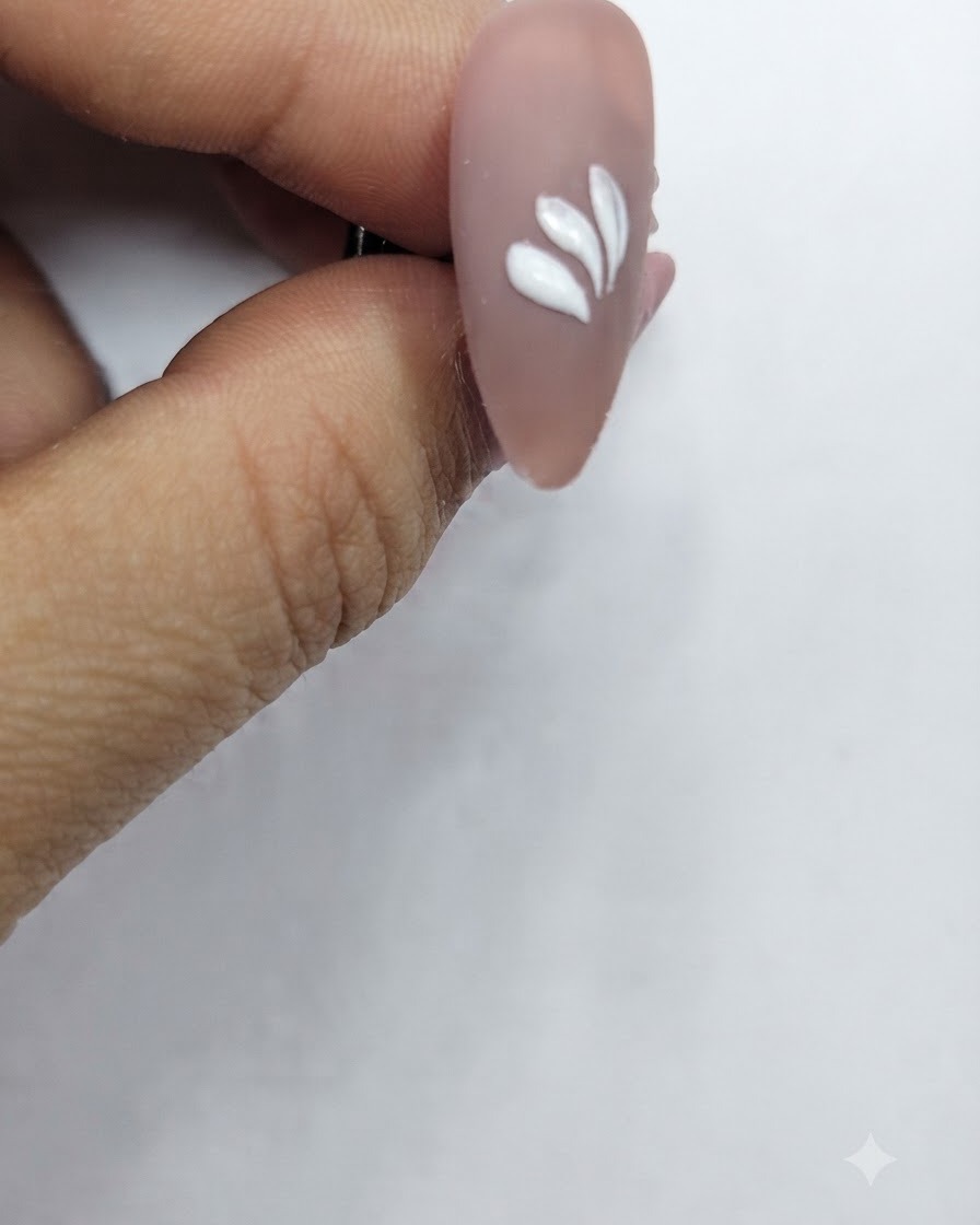 円形を少し崩した配置で複数の白い花びらのストロークが描かれているネイル。