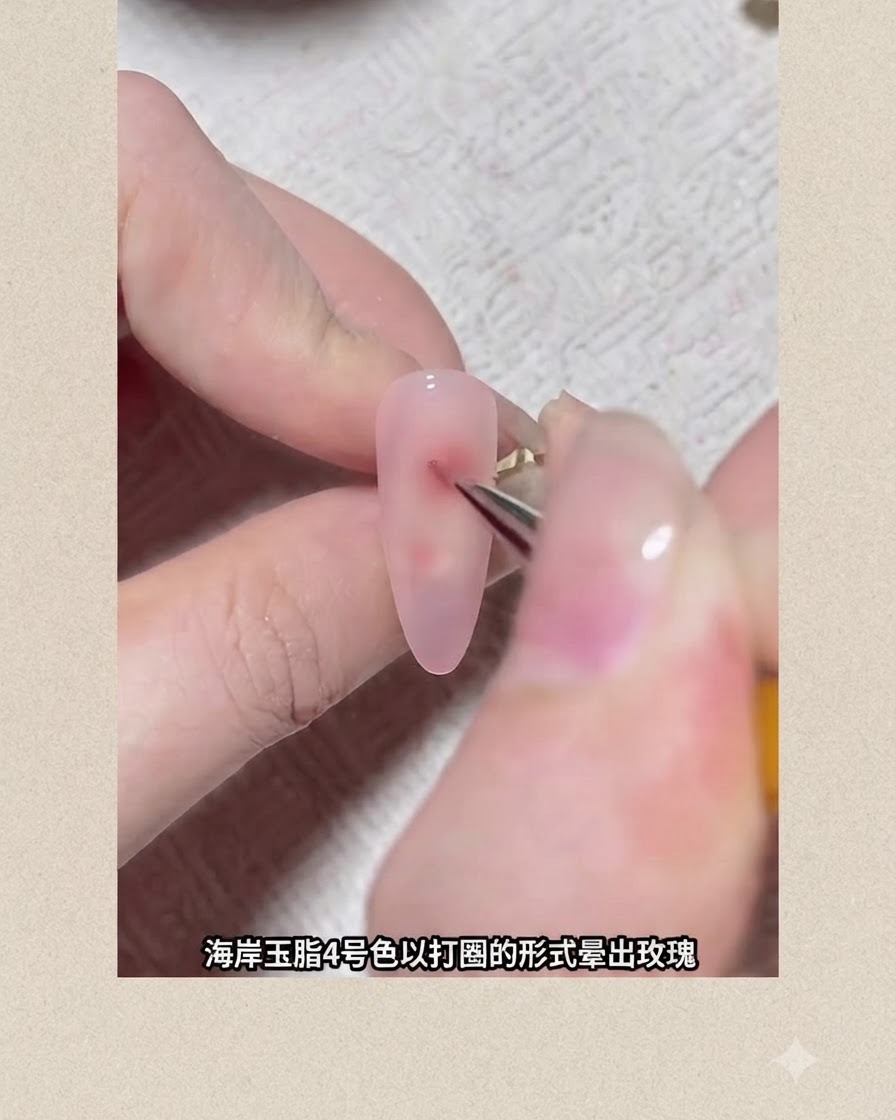 ブルーミングフラワーを形作るために、ピンクのジェルが塗られた爪の上に赤い円形のピグメントのドットを描いている細いネイルアートブラシ。