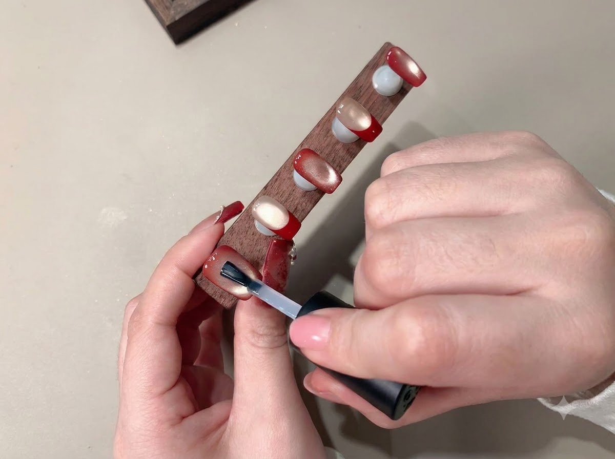 仕上げられたネイルアートをシールするためにクリアトップコートを塗布しているブラシ。