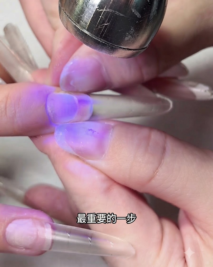 紫色のUVライトの下でネイルエクステンションの両サイドを指でつまんでいる様子。