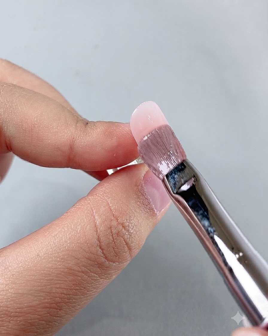 ネイルの施術中、キューティクル周辺のプロダクトをマニキュアブラシで整えている様子。