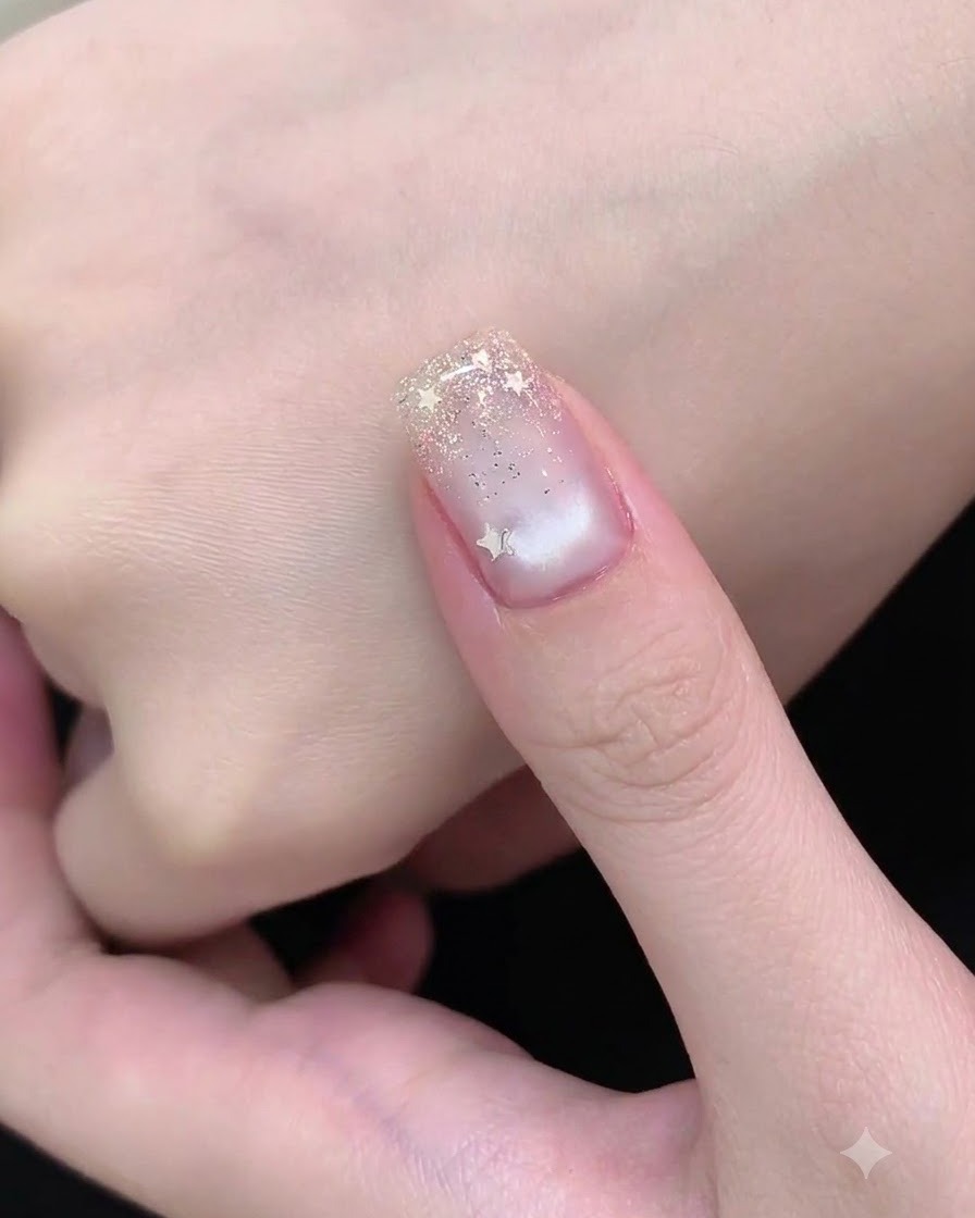 ネイルアート用の筆を使い、細かいシルバーラメを爪の先端にポンポンと乗せてグラデーションを作っている様子。
