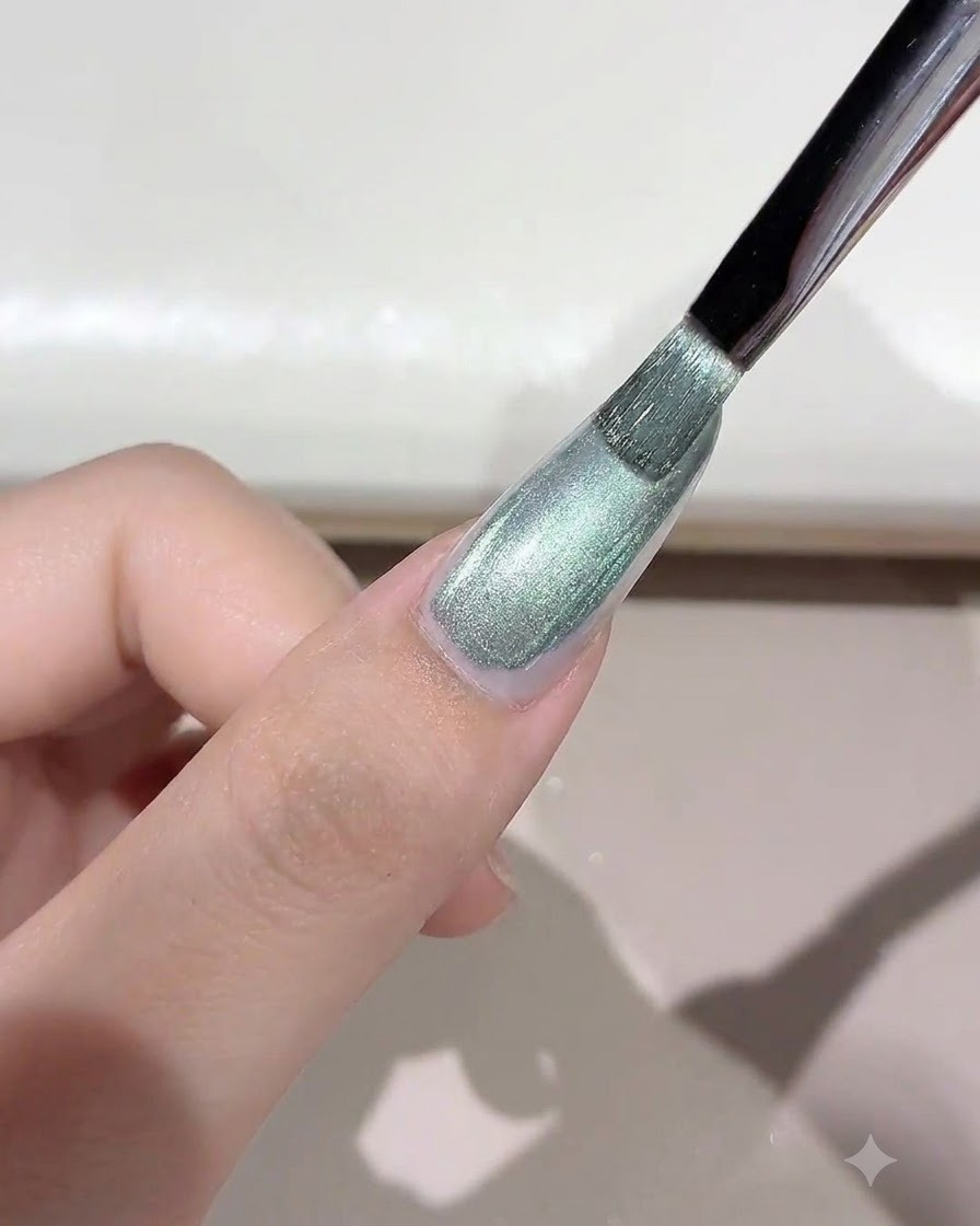 グリーン系のきらめくワイルドキャッツアイジェルをブラシでネイルに塗布している様子。