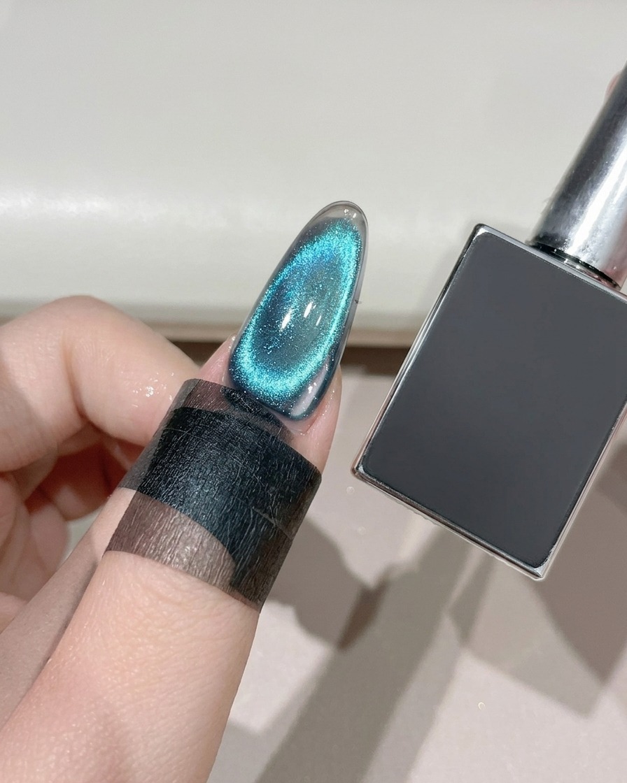 ダークジェルボトルの隣で、UV/LEDランプの下で硬化されている完成したキャッツアイネイル。