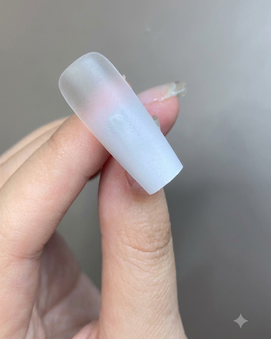 グラデーションネイルの表面に、半透明のミルキーホワイトのジェルが薄く塗られている様子。