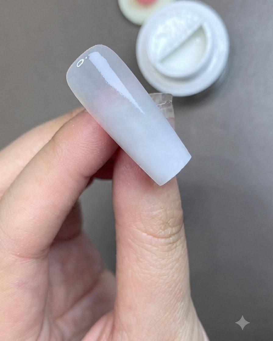ミルキーホワイトの下地が整ったネイルの上に、ブラシがマットトップコートをなめらかに塗っている様子。