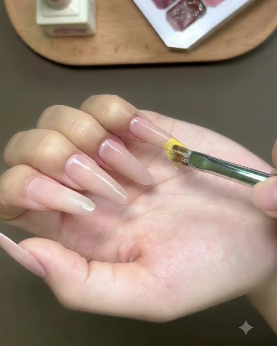ロングアーモンドネイルの先端にイエロージェルをブラシで塗布している様子。