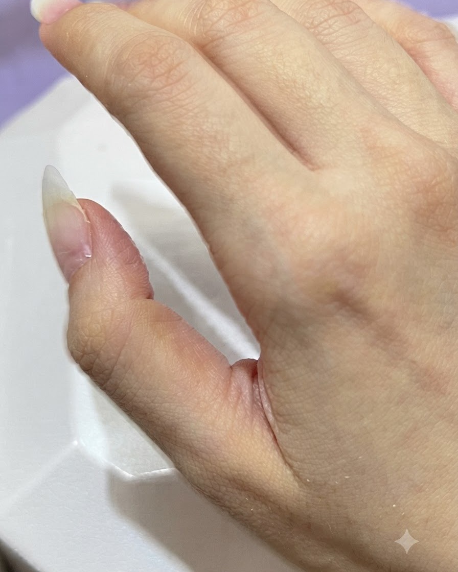 シンプルな背景をバックに、きれいに整えられた素のアーモンド型ネイルを見せている手。