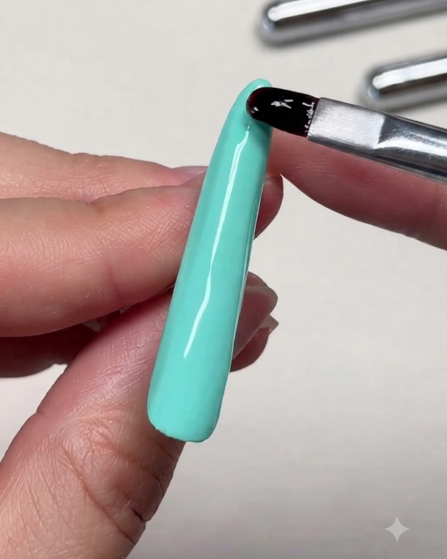ロングネイルの先端付近で、補強用ジェルを筆でレベリングしているクローズアップ画像。