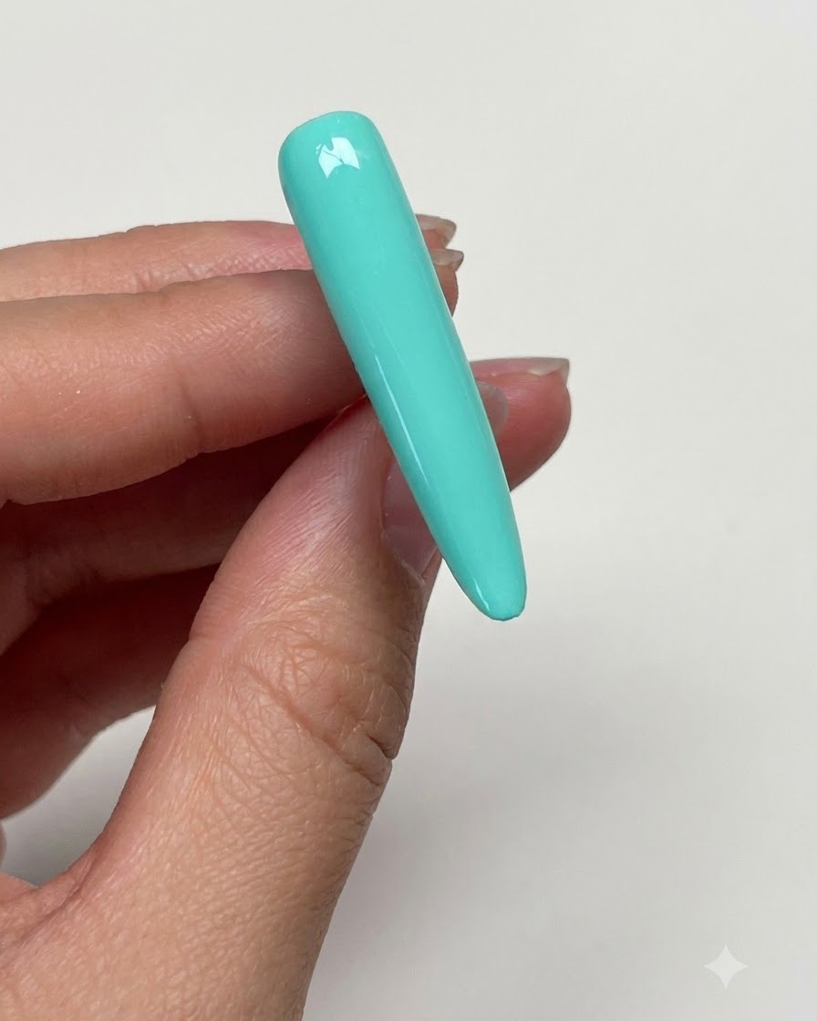 硬化後のミントグリーンネイルの表面を、アルコールパッドで拭き取ってベタつきを除去している手。