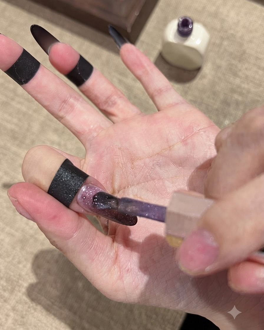 ダークなグラデーションのベースネイルの上に、ブラシでフォーレンゴールドキャッツアイジェルポリッシュを塗布している様子。