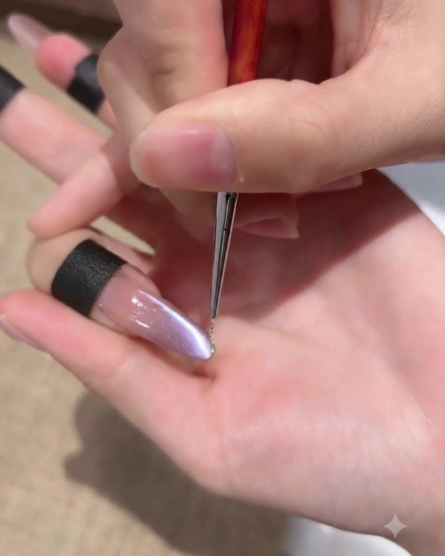 極細のライナーブラシを使って、パープルキャッツアイネイルのサイドウォールに沿ってキラキラ光るシルバージェルの極細ラインを描いている様子。