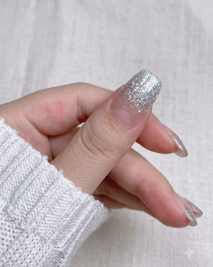 小さなマニキュア用ハサミで先端に沿って余分なネイルラップのストリップを切り取っているクローズアップビュー。