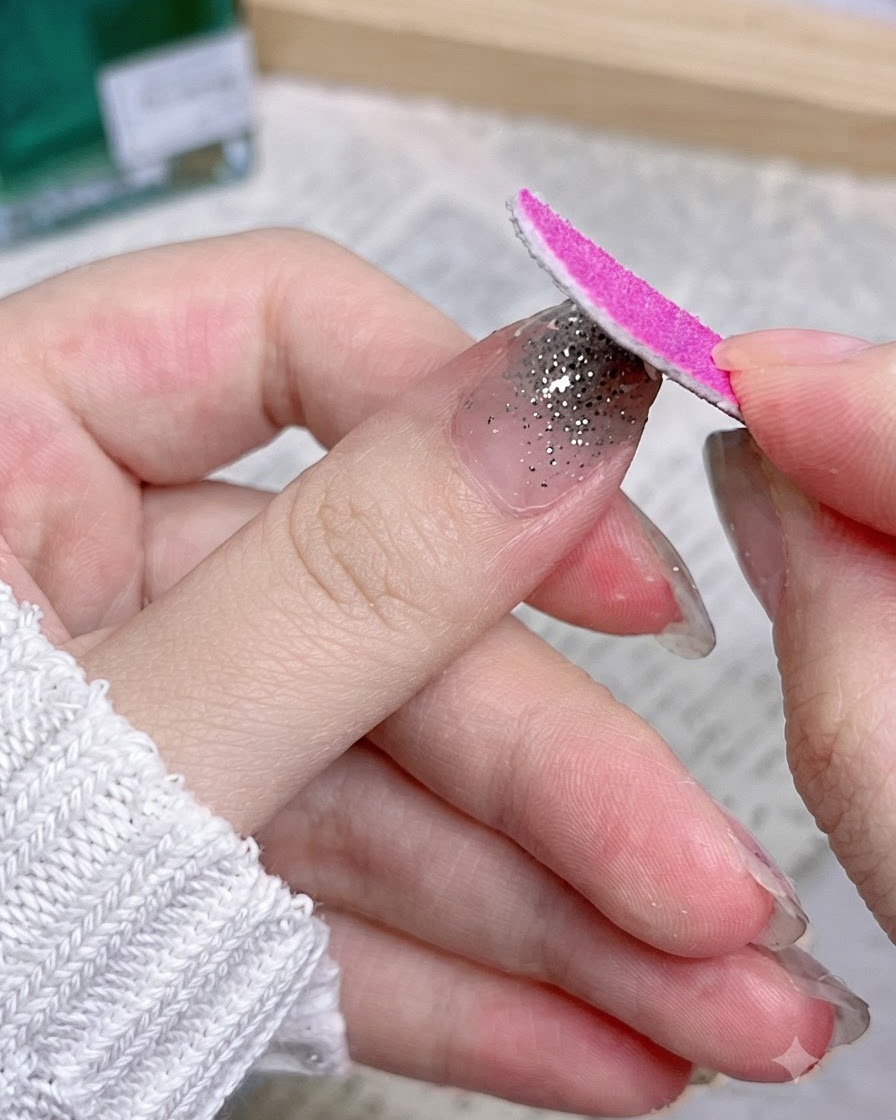 余分なラップ素材を取り除くため、爪の端に沿って下向きに動くピンクのネイルファイル。
