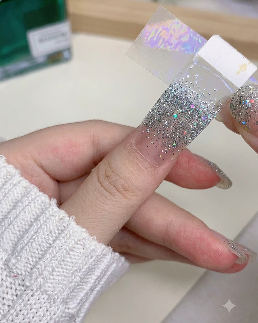 ネイルチップの縁を専用ツールで慎重に削り、形を整えている手元のクローズアップ画像。