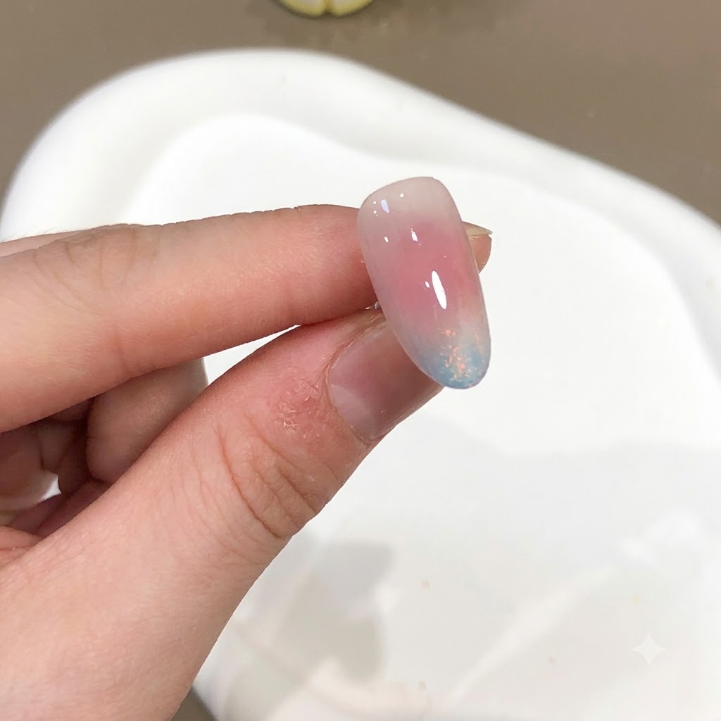ハイグロス仕上げのピンクとブルーのオーロラパウダー効果を示すネイルのクローズアップ。