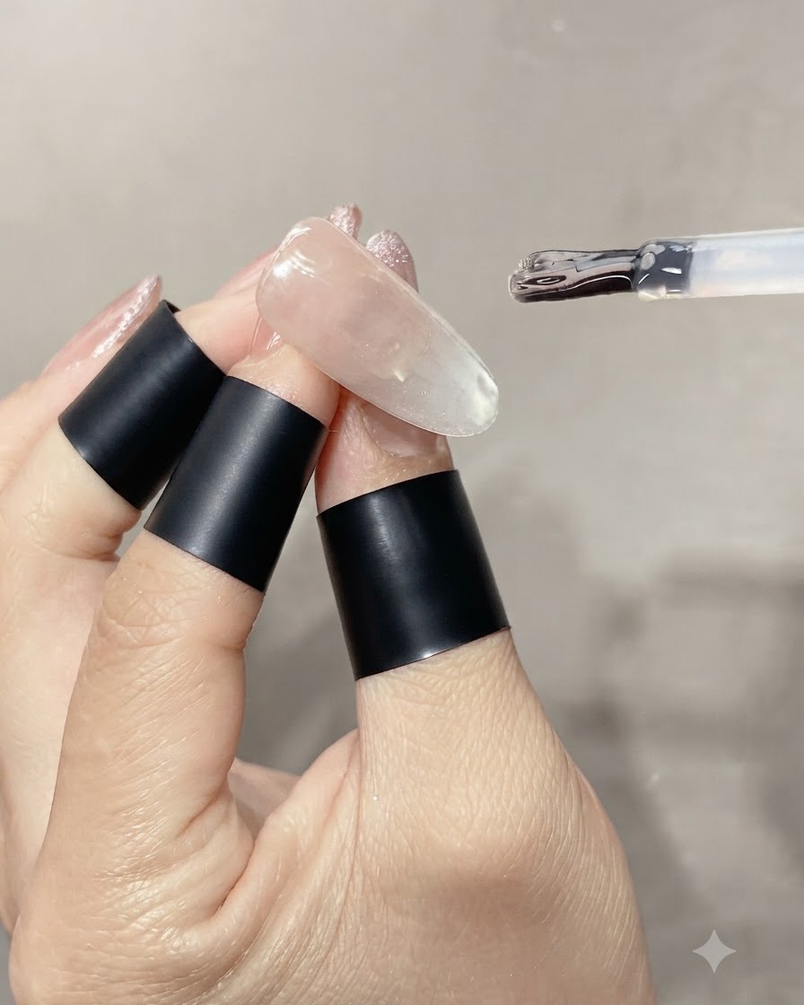 完成したガラス玉キャッツアイネイルの上に、クリアで艶のあるトップコートを厚めに塗っている様子。